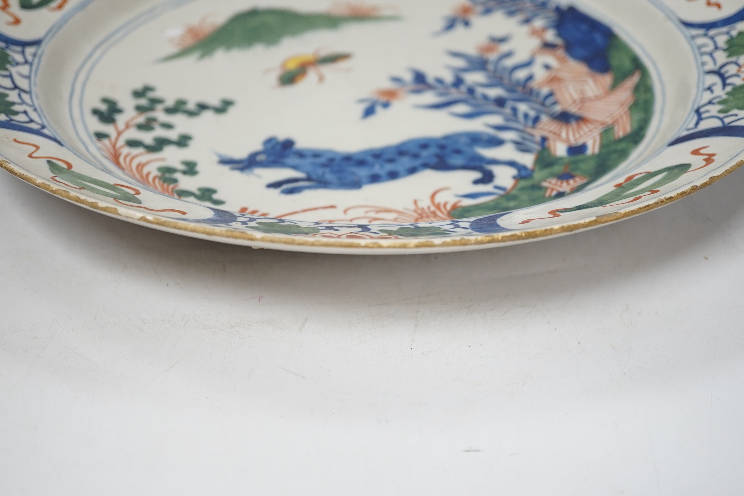 An 18th century delftware dish, the centre painted with a wolf, a bee and a pavilion, 35cm